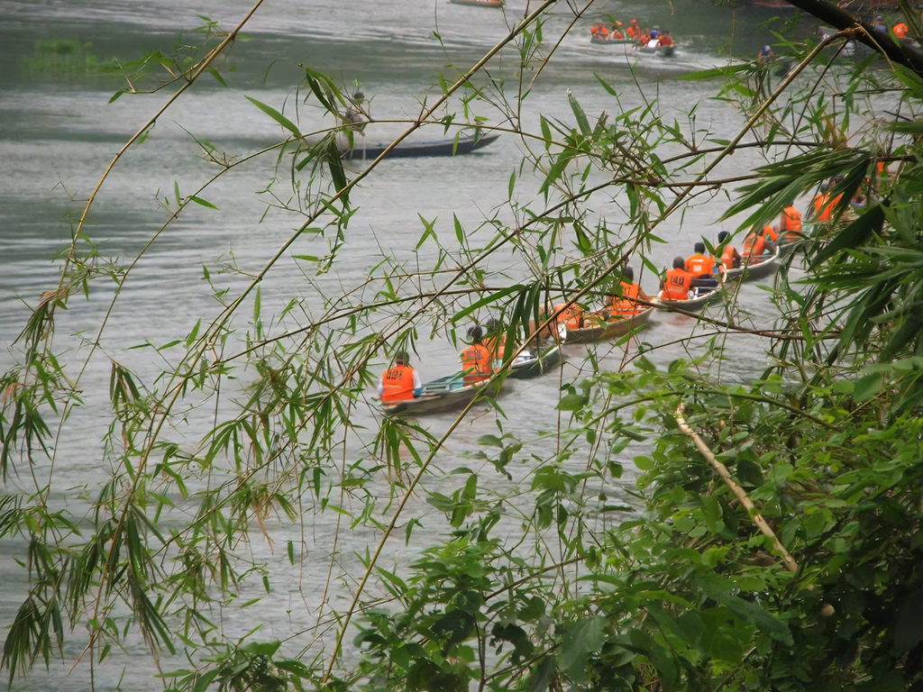A string of canoes is navigating through the river gorge towards Pagsanjan Falls.