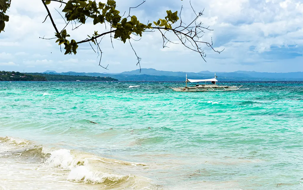 A view from the white sand beach of Panglao Island overlooking a Banka in the water. It's a gorgeous scene!