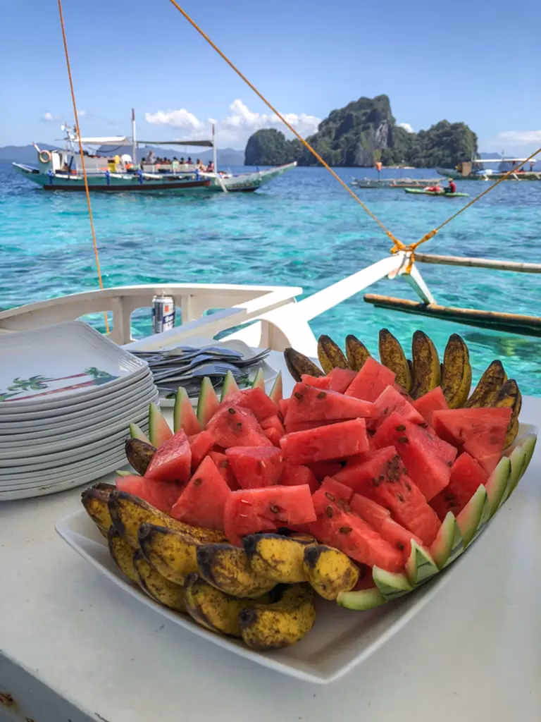 A picture of some snacks on a small boat used for island hopping in the Philippines. There are several other boats in the picture as well.